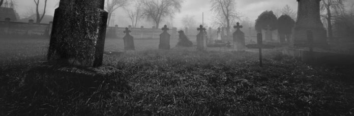 Old creepy graveyard on stormy winter day in black and white